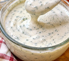 Ciotola di salsa ranch cremosa a base di fiocchi di latte, con erbe aromatiche fresche e verdure da intingere sul bordo