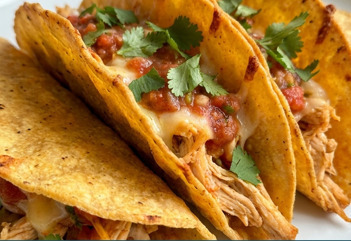 Tacos di pollo croccanti al forno su teglia, con formaggio dorato e tortillas di mais piegate, pronti da servire